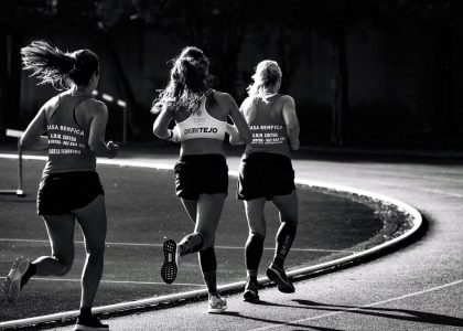 Black and white back view of unrecognizable fit female runners in sportswear running during track and field competition