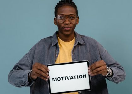 A young African American man holding a tablet displaying the word 'MOTIVATION' against a blue background.